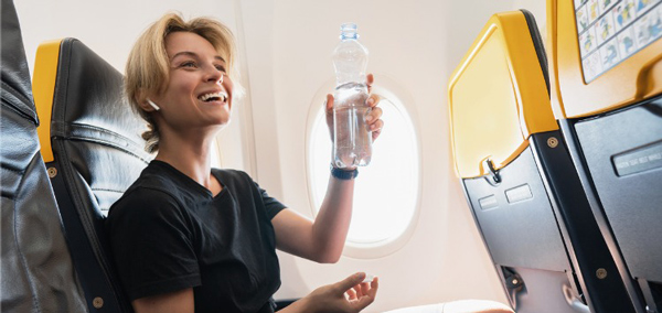 Mulher se hidratando no voo para evitar sintomas de jet lag.