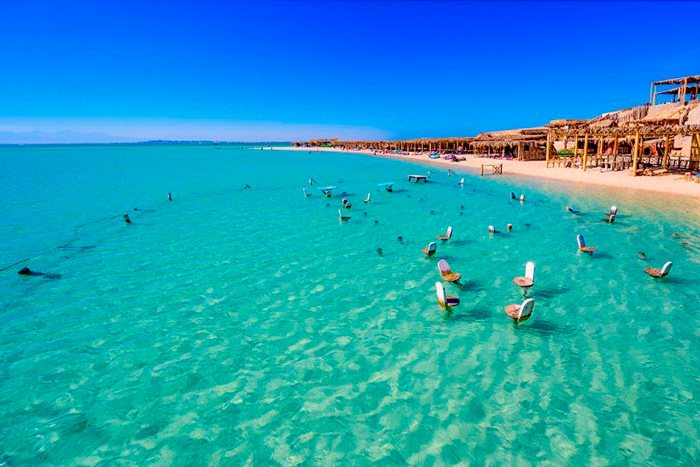 Resort na praia, com cadeiras dentro da parte rasa no mar vermelho.