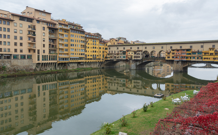 Roteiro pela Toscana em Lucca, com casas históricas às margens do rio e a ponte medieval refletida na água 