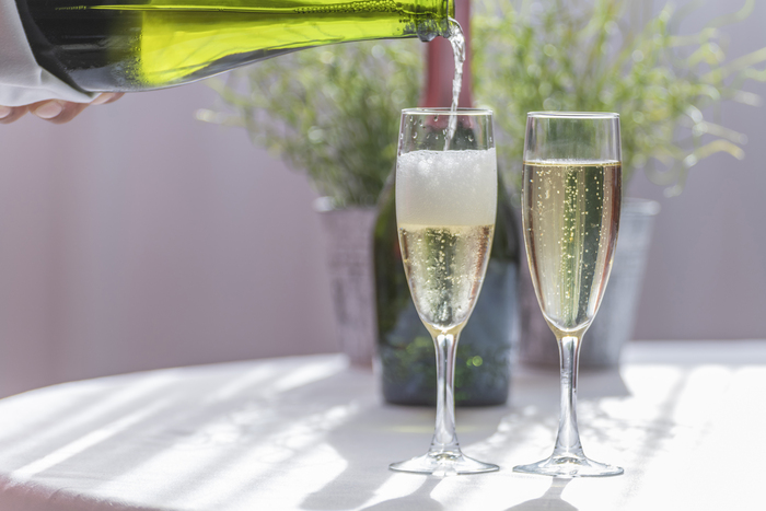 Duas paças de champagne sendo servidas sobre uma mesa.