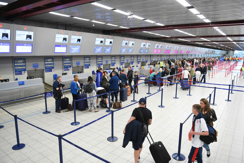 Pessoas em fila do aeroporto para embarcar com sua bagagem de mão.