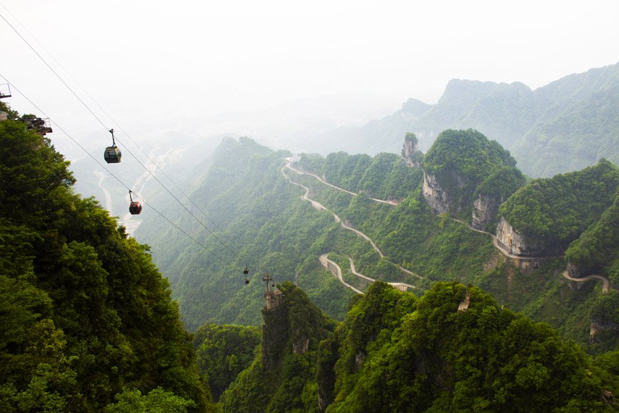 Teleférico na montanha Tianmen, com estrada cheia de curvas ao fundo.