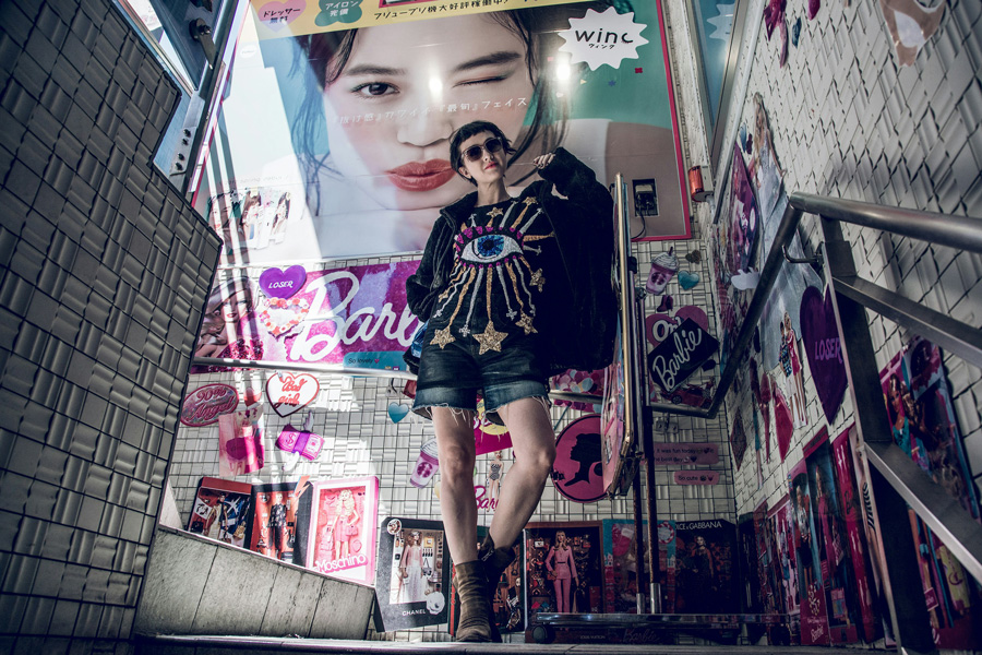 Visitante em Harajuku entre anúncios coloridos de moda jovem em Tóquio