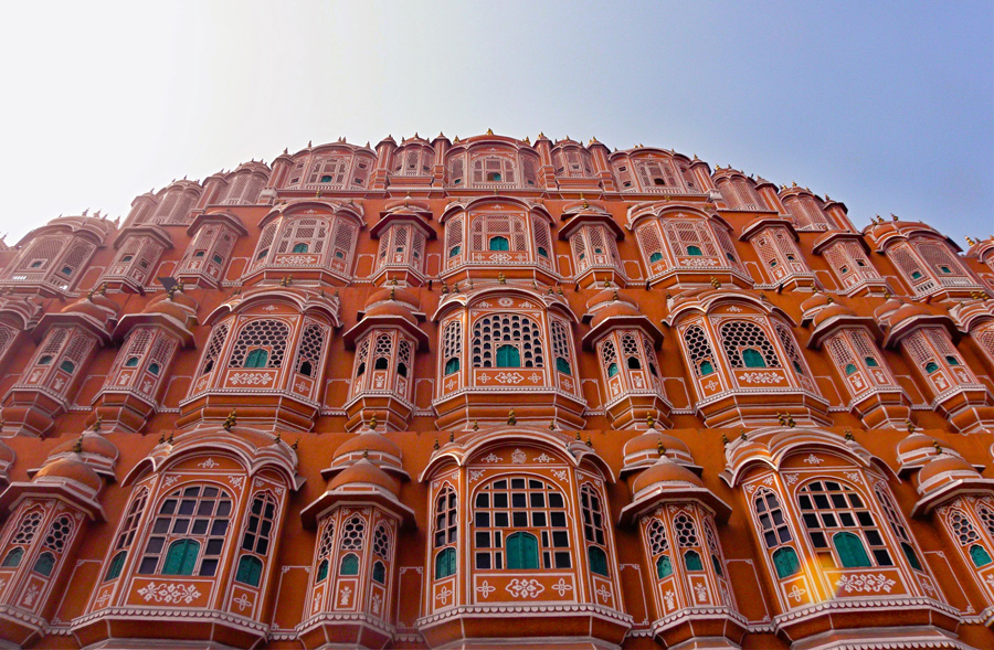Fachada rosa do Hawa Mahal, o Palácio dos Ventos, vista de baixo, com centenas de pequenas janelas, em Jaipur, na Índia.